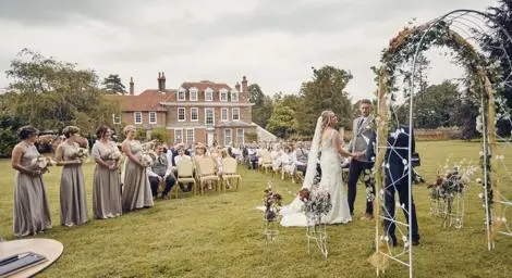 Bride and groom getting married outside under a floral arch at Abbott's Hall