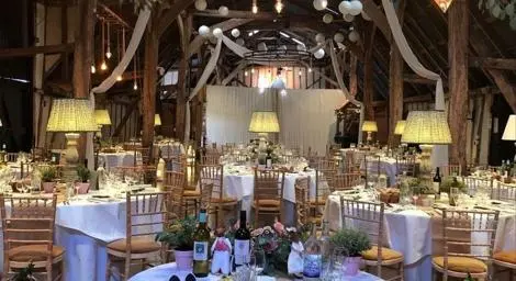Round table with flowers and wine set on the table. Hanging lights and plants from the ceiling.