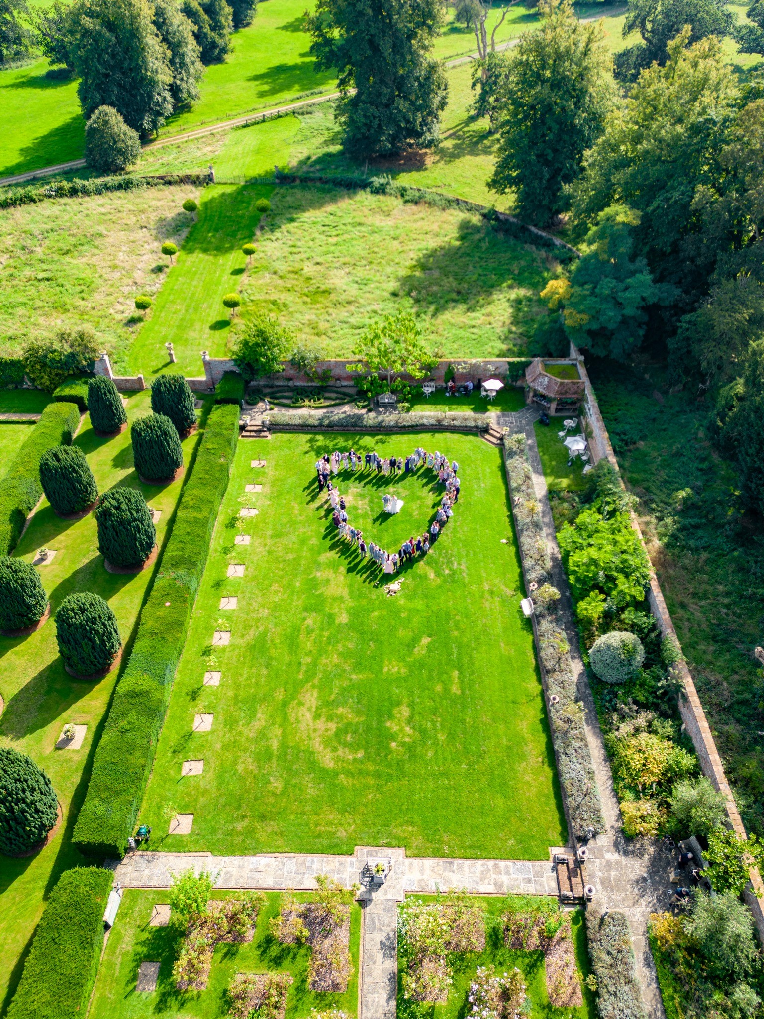 Heart formed by wedding guests on lawn