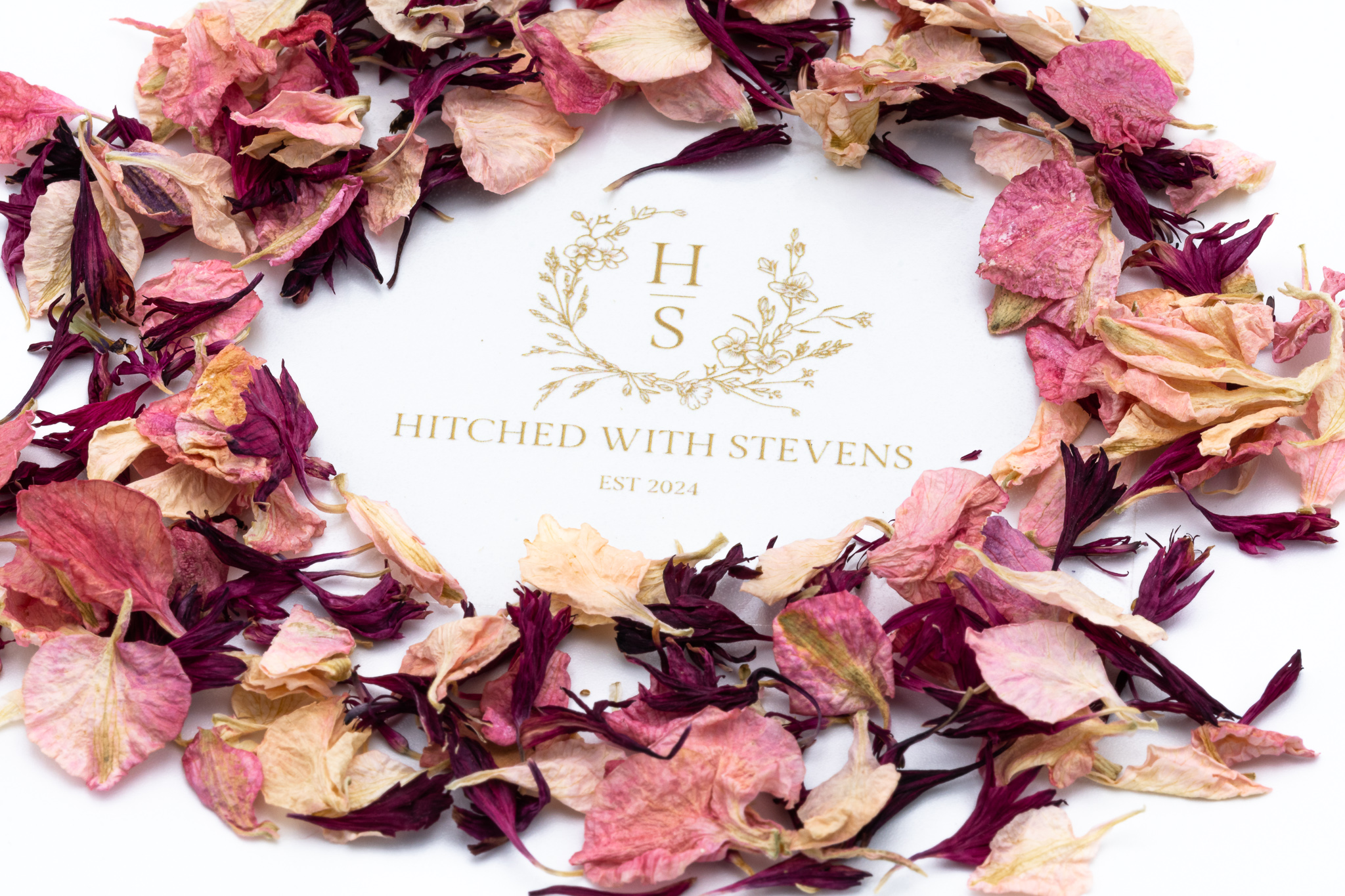 Red and pink flower leaf confetti in a circle around a logo