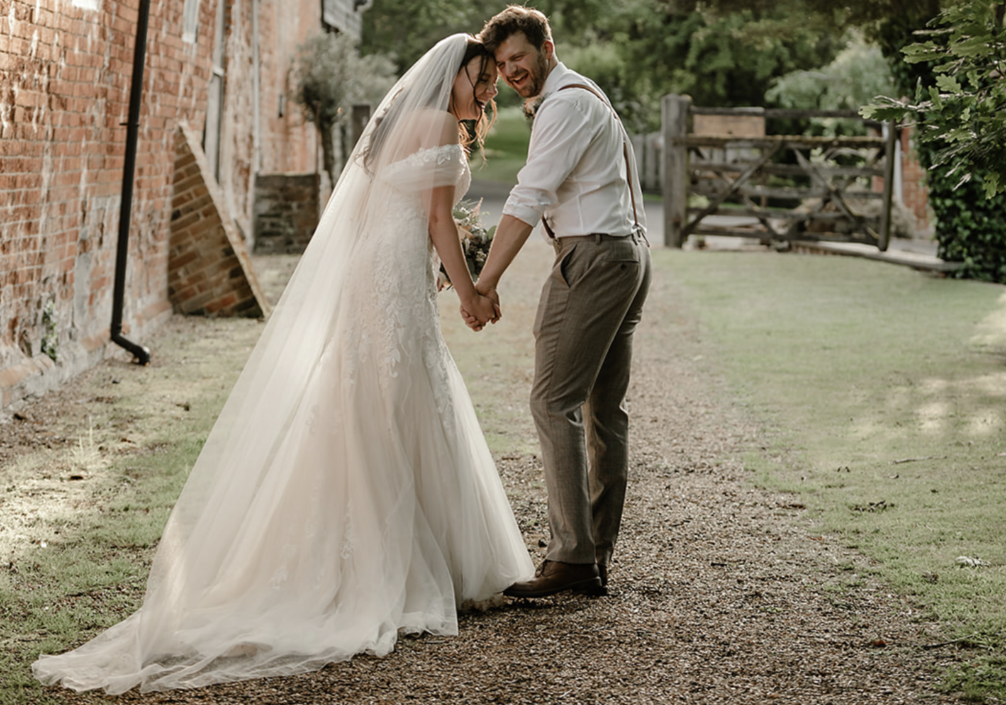 Bride and groom laughing together in courtyard