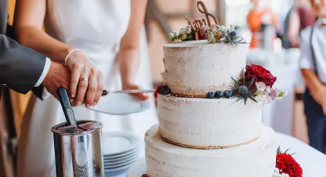 Bride and groom cutting through the second later of their wedding cake.