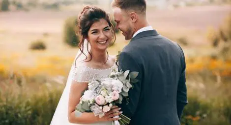 Young bride and groom outside in a field.