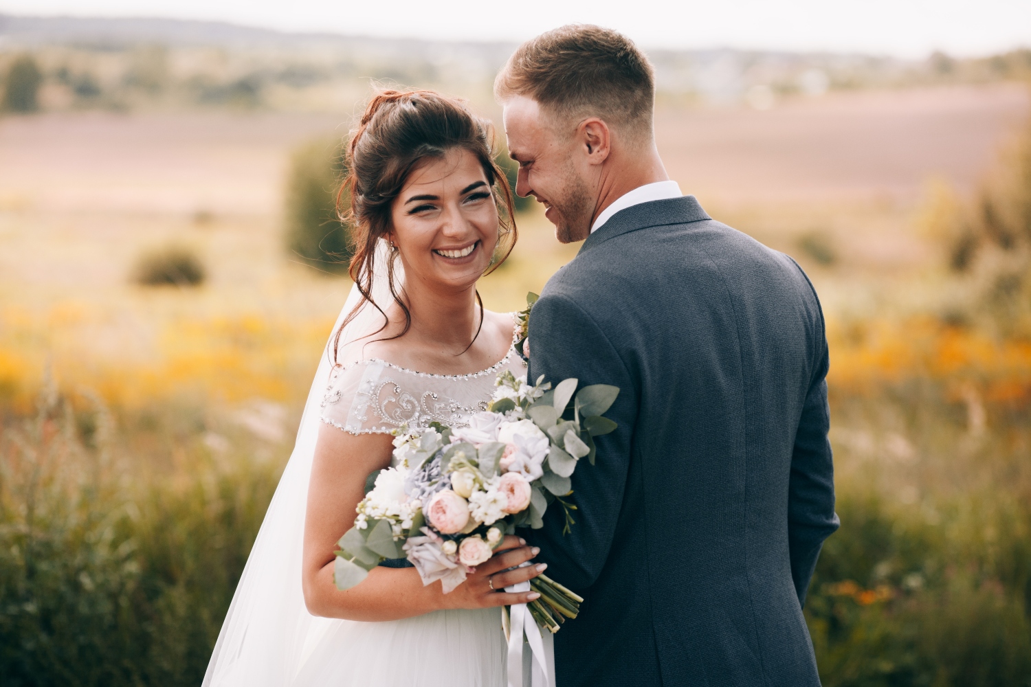 Young bride and groom outside in a field.