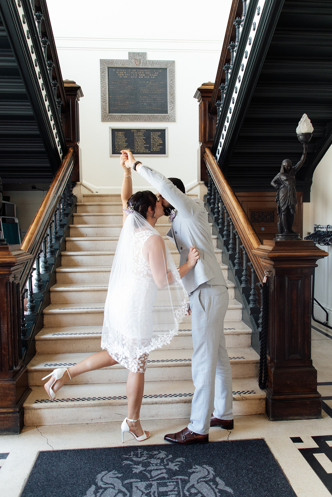 Bride and groom twirling while kissing in front of the staircase in Ipswich Town Hall