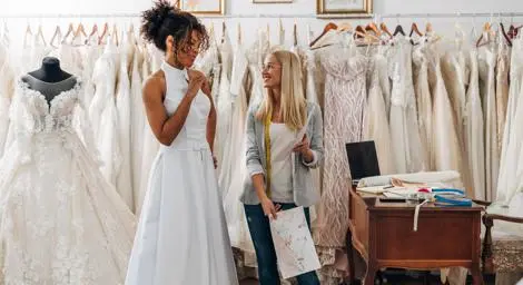 Black bride in her wedding dress chatting with her dress fitter.