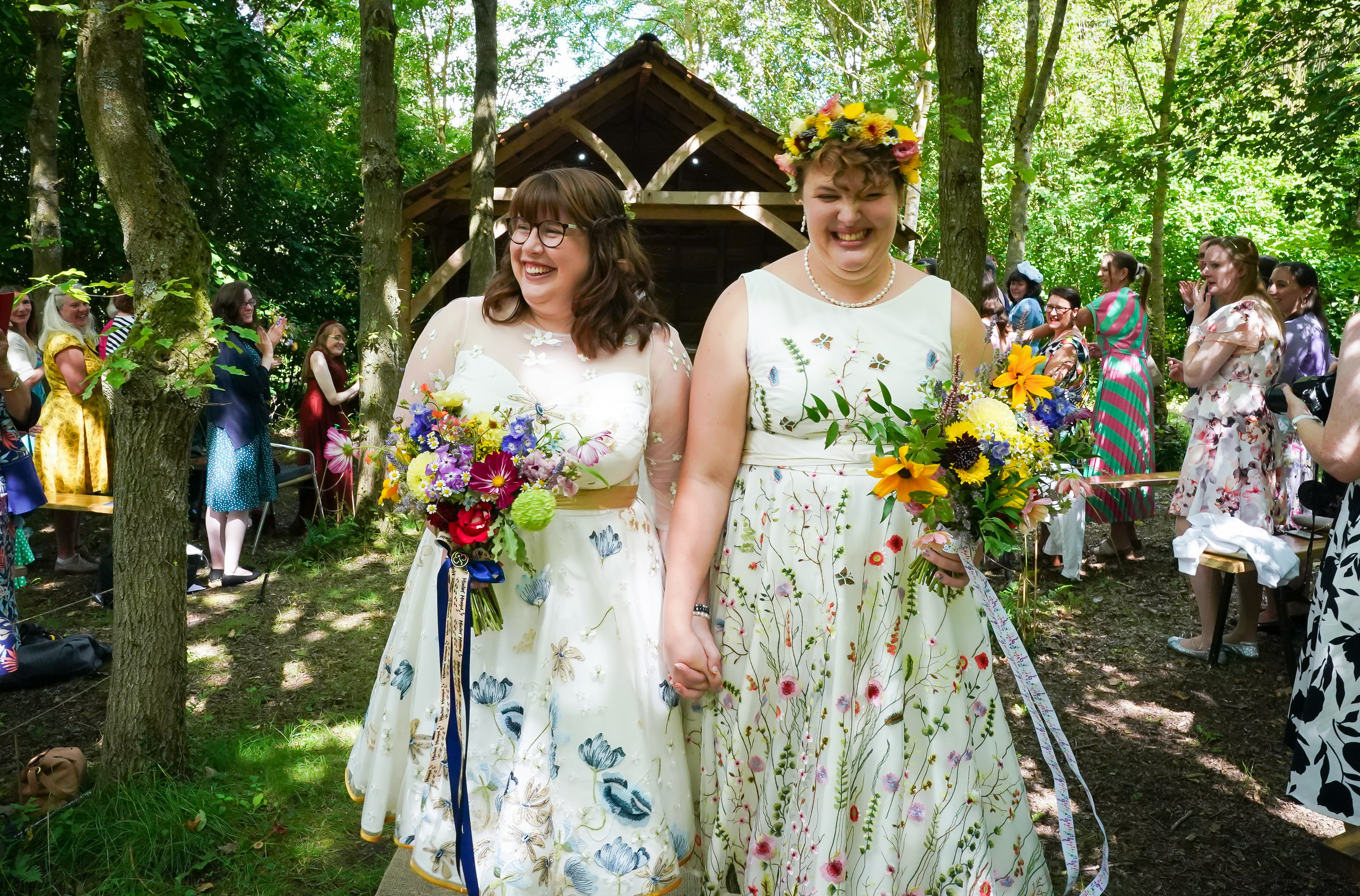Two women just married holding hands walking back up the aisle. 