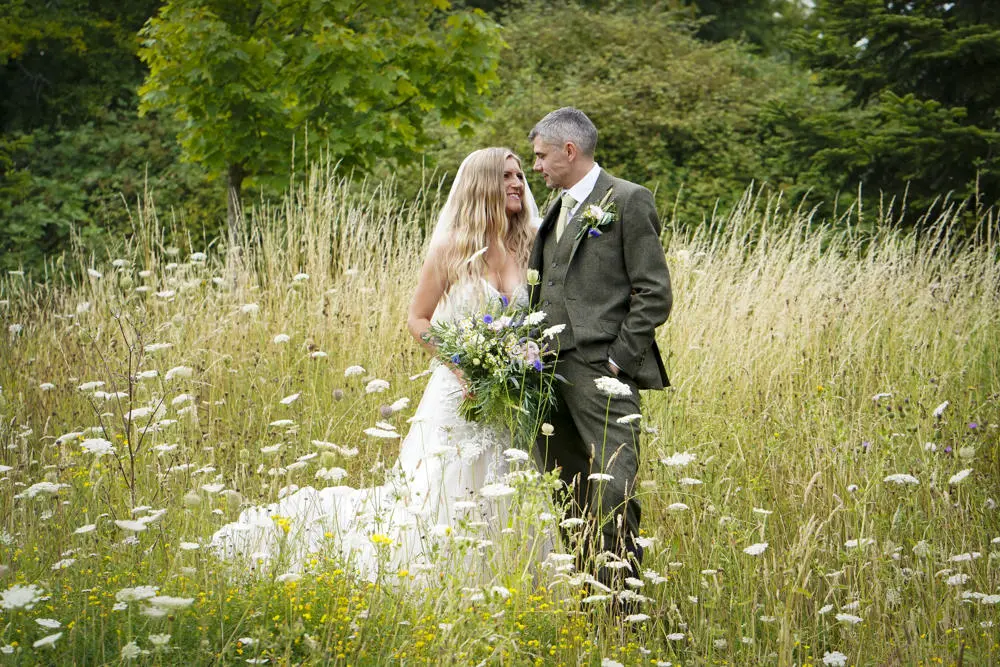Bride and groom in meadow gazing at each other. Photographer Buffy Thompson