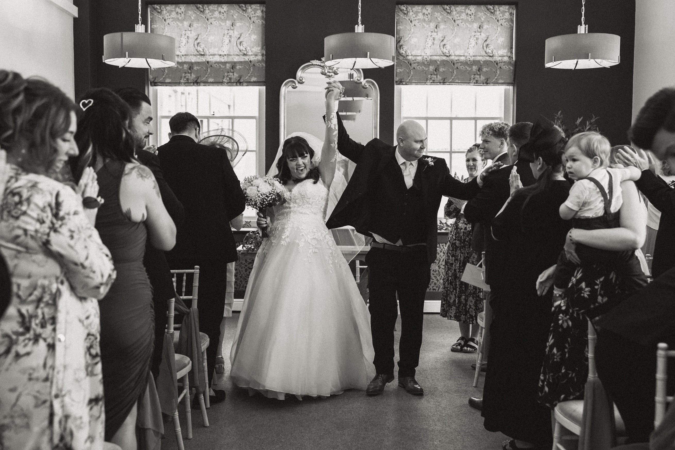 Black and white photo bride and groom celebrating in Bury Register Office
