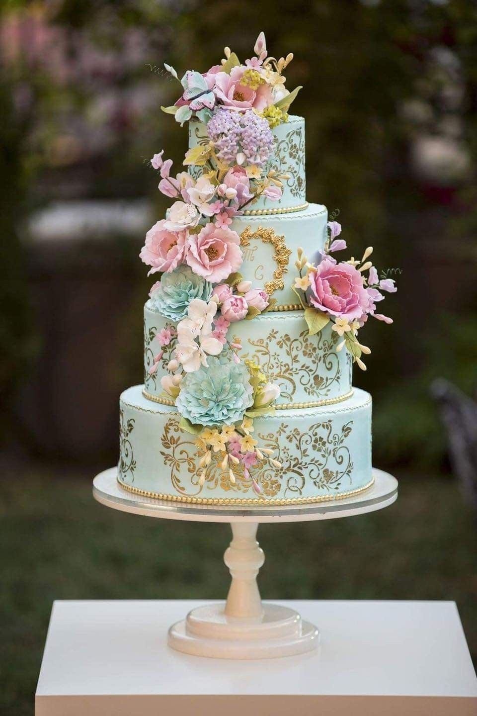 Bridgerton style four tier wedding cake with extravagant floral decorations