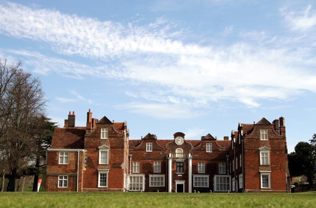 Christchurch Mansion with grass in front and trees behind.