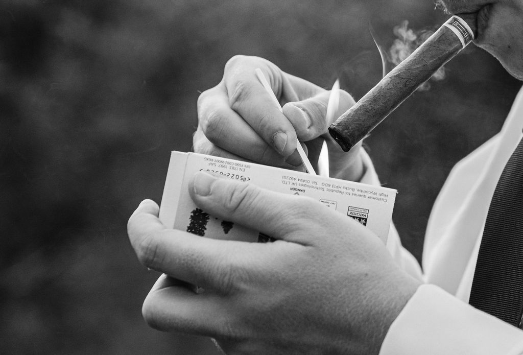 black and white image hands striking match to light cigar