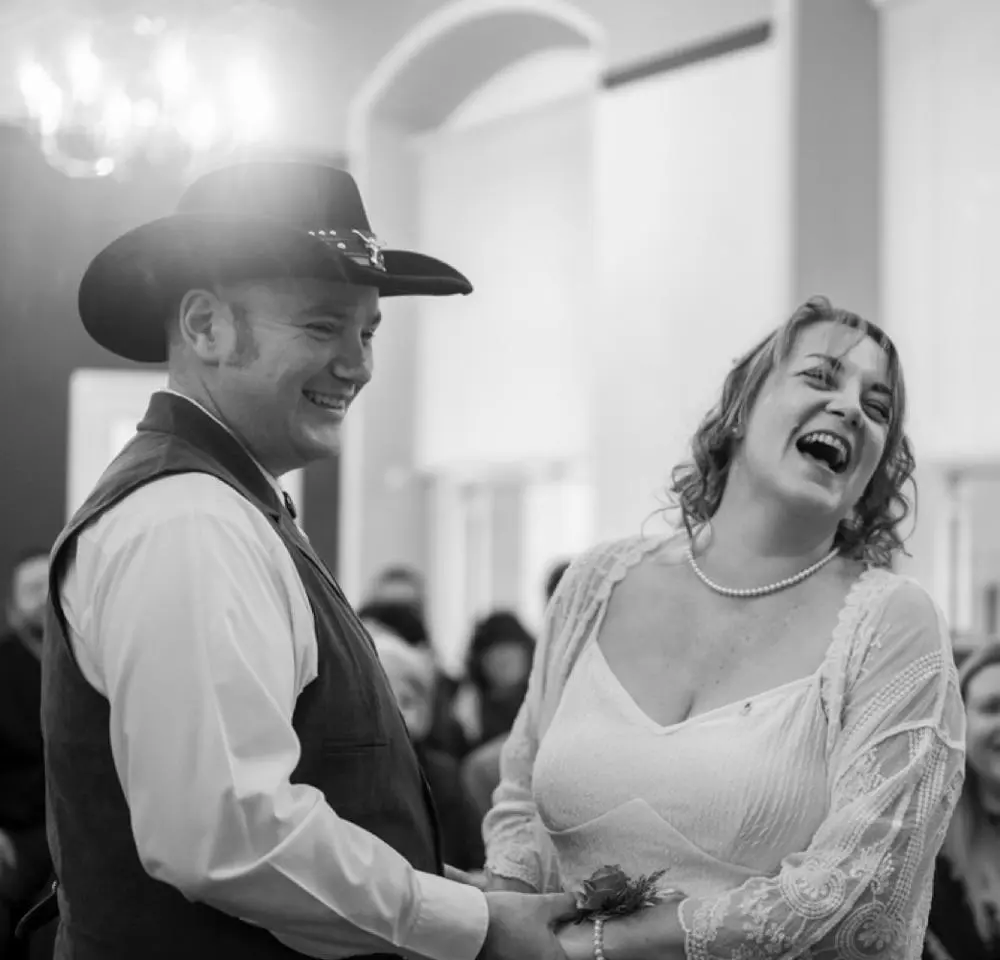 An intimate indoor moment of the couple during their ceremony, holding hands and sharing a warm, emotional connection.