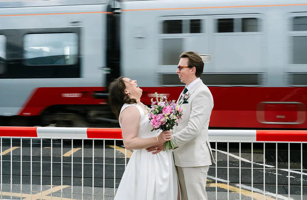 Bride and groom at level crossing with train passing in background