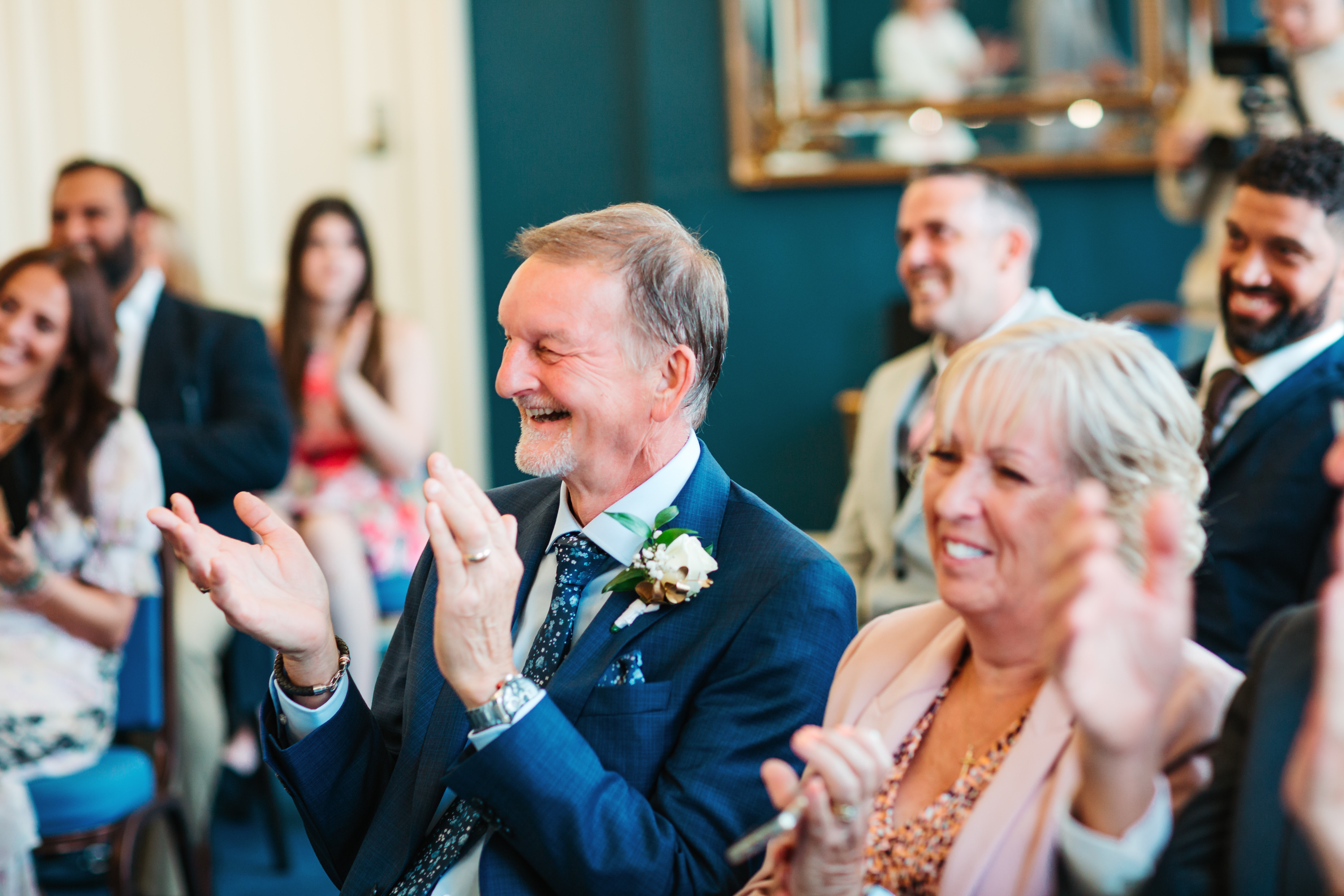 Parents of the bride and groom smiling and clapping in ceremony.