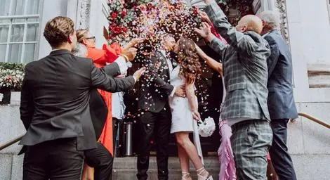 Bride and groom kissing on steps in a shower of confetti