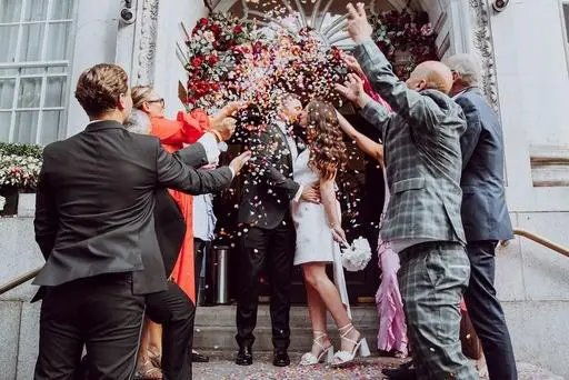 Bride and groom ion steps kissing in a shower of confetti