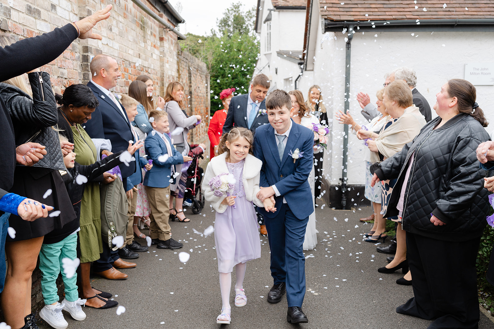 Boy and girl walking out of a wedding ceremony in front of their parents
