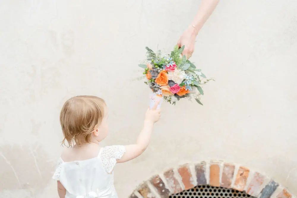 Little girl being handed wedding bouquet of colourful flowers
