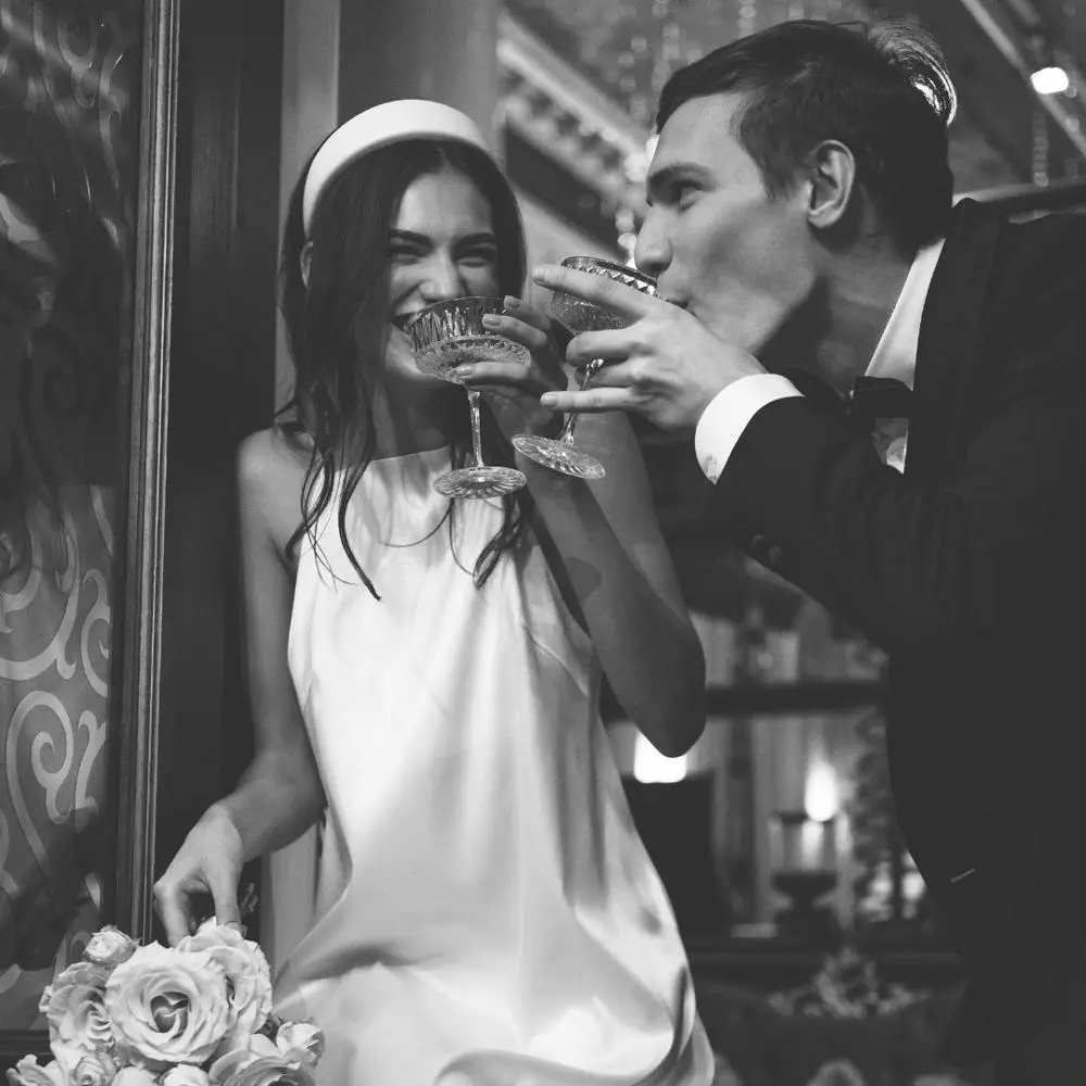 Black and white image of bride and groom having a cocktail, smiling