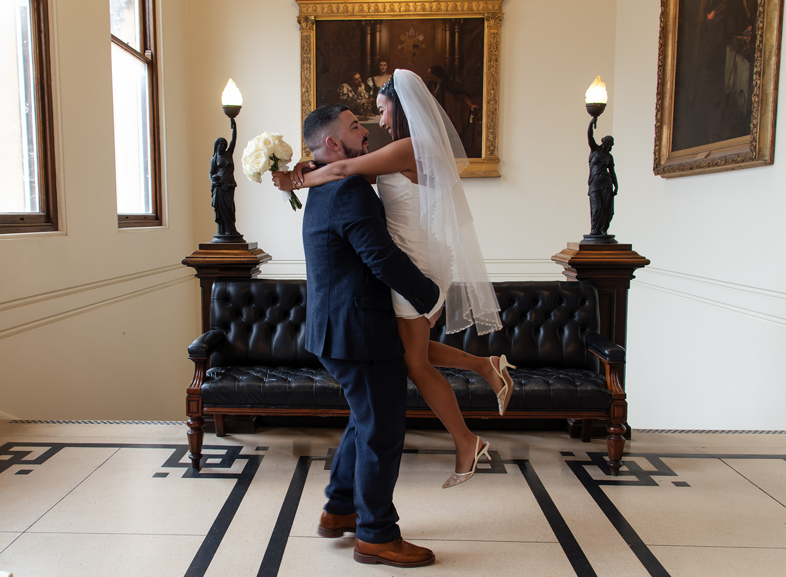 Groom lifting smiling bride Ipswich Town Hall