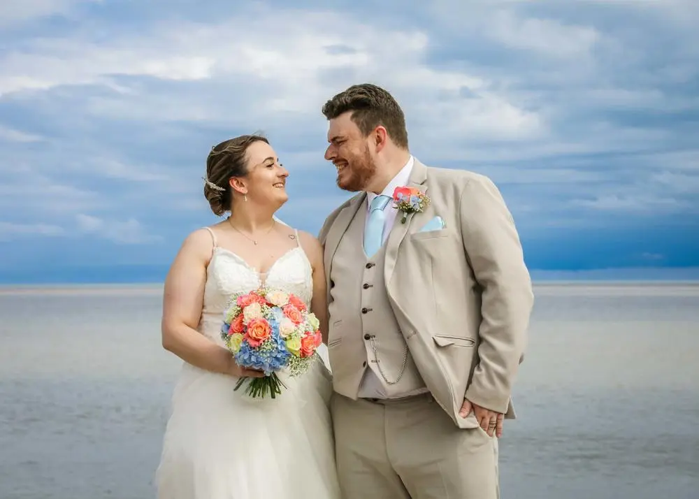 Bride and groom at beach beaming at each other