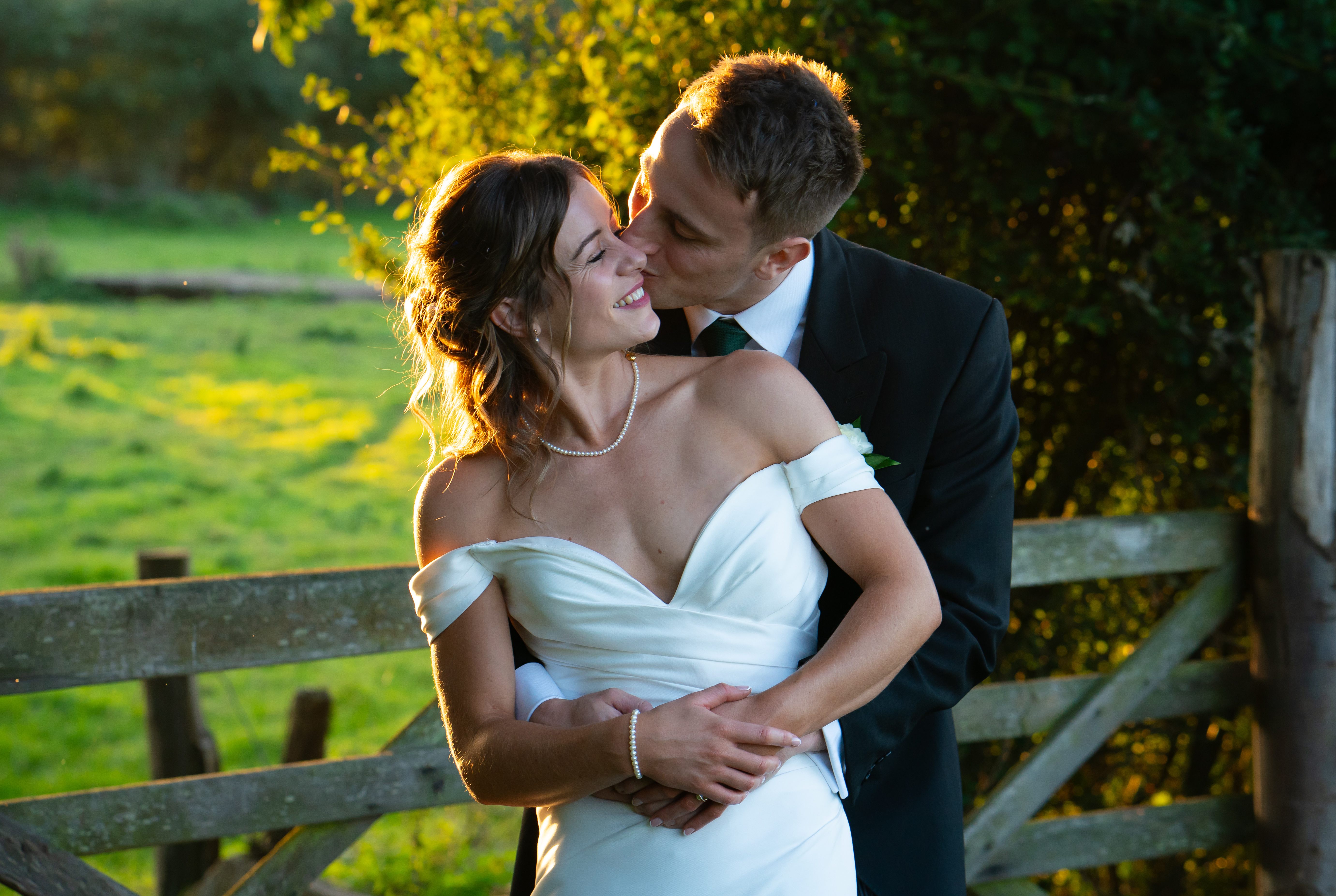 Groom hugging bride and kissing her on the cheek.