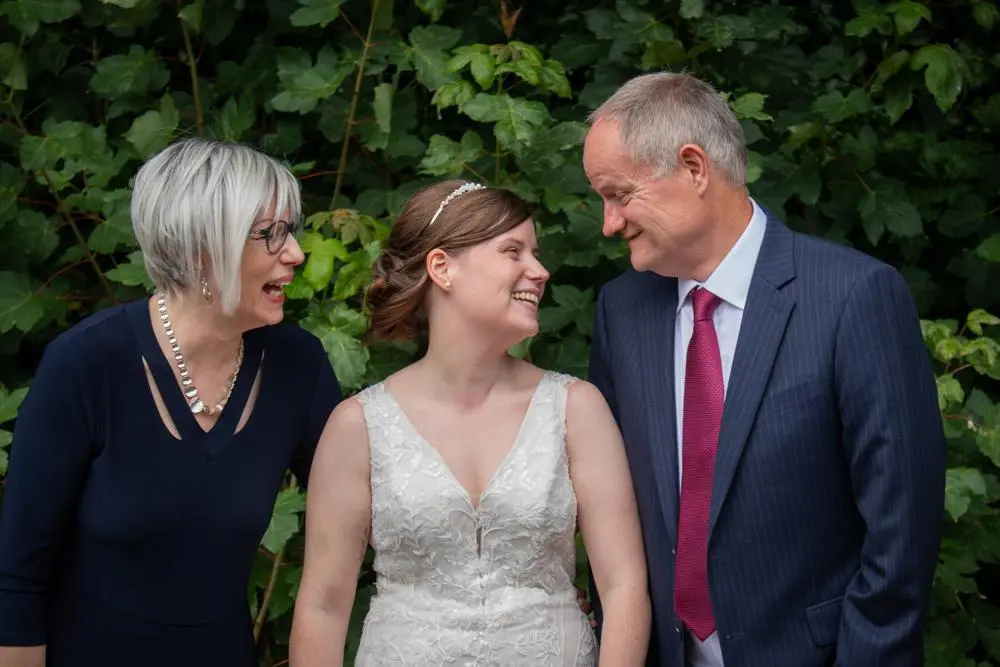Bride flanked by her parents, all smiling happily at each other