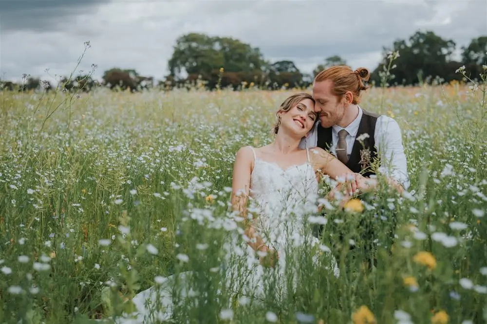 Couple just married sitting together in a meadow smiling blissfully