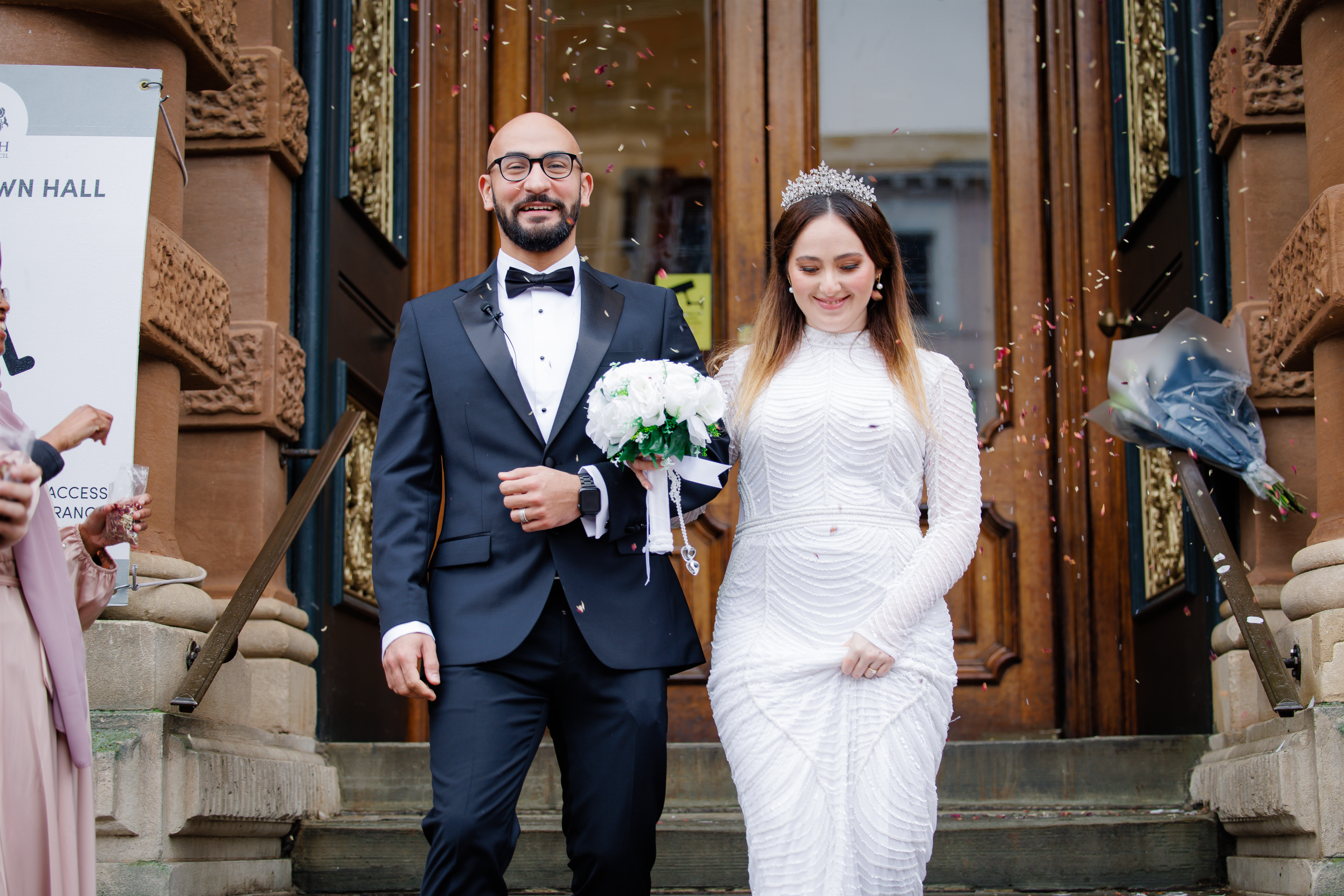 Bride and groom arm in arm after getting married with confetti thrown at them
