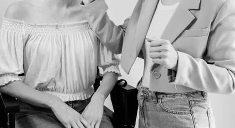 Make up artist applying lip gloss to a woman sitting in a chair