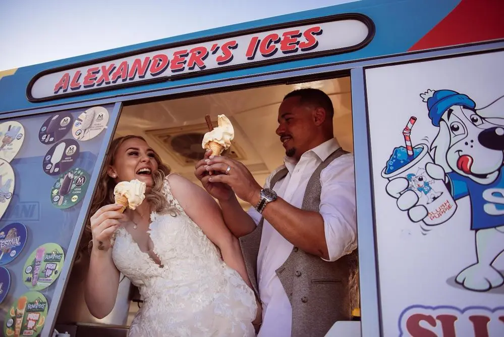 Bride and groom eating ice cream in a van