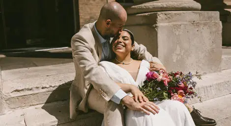 Bride and groom sitting in the sun on the steps of the Corn Exchange in Bury St Edmunds