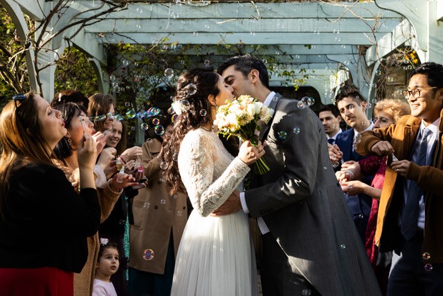 Bride and groom kissing amongst their friends