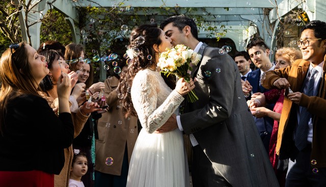 Bride and Groom kissing surrounded by friends