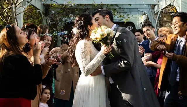 Bride and Groom kissing surrounded by friends