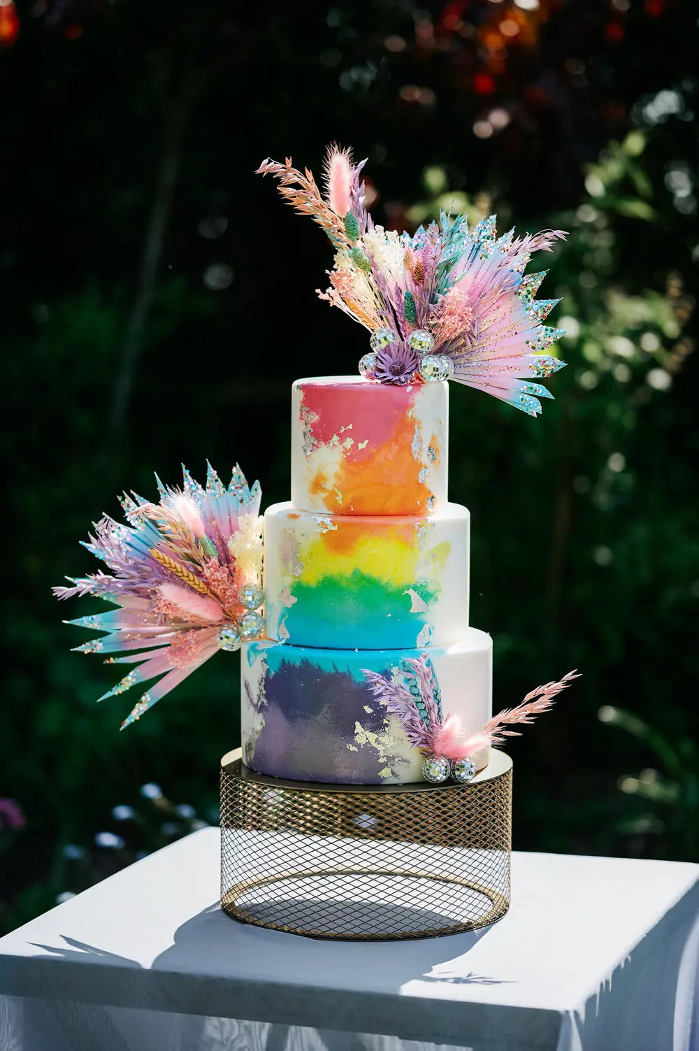 Three tier rainbow coloured cake with decorations
