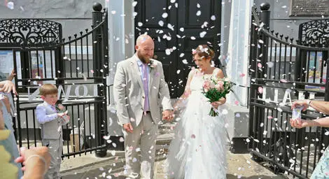 Bride and groom celebrating in a shower of petal confetti outside Sudbury Town Hall