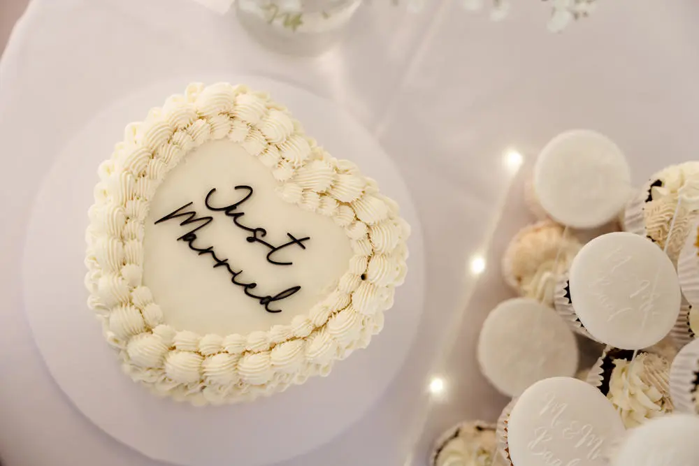 Heart-shaped wedding cake with ‘Just Married’ written in black script