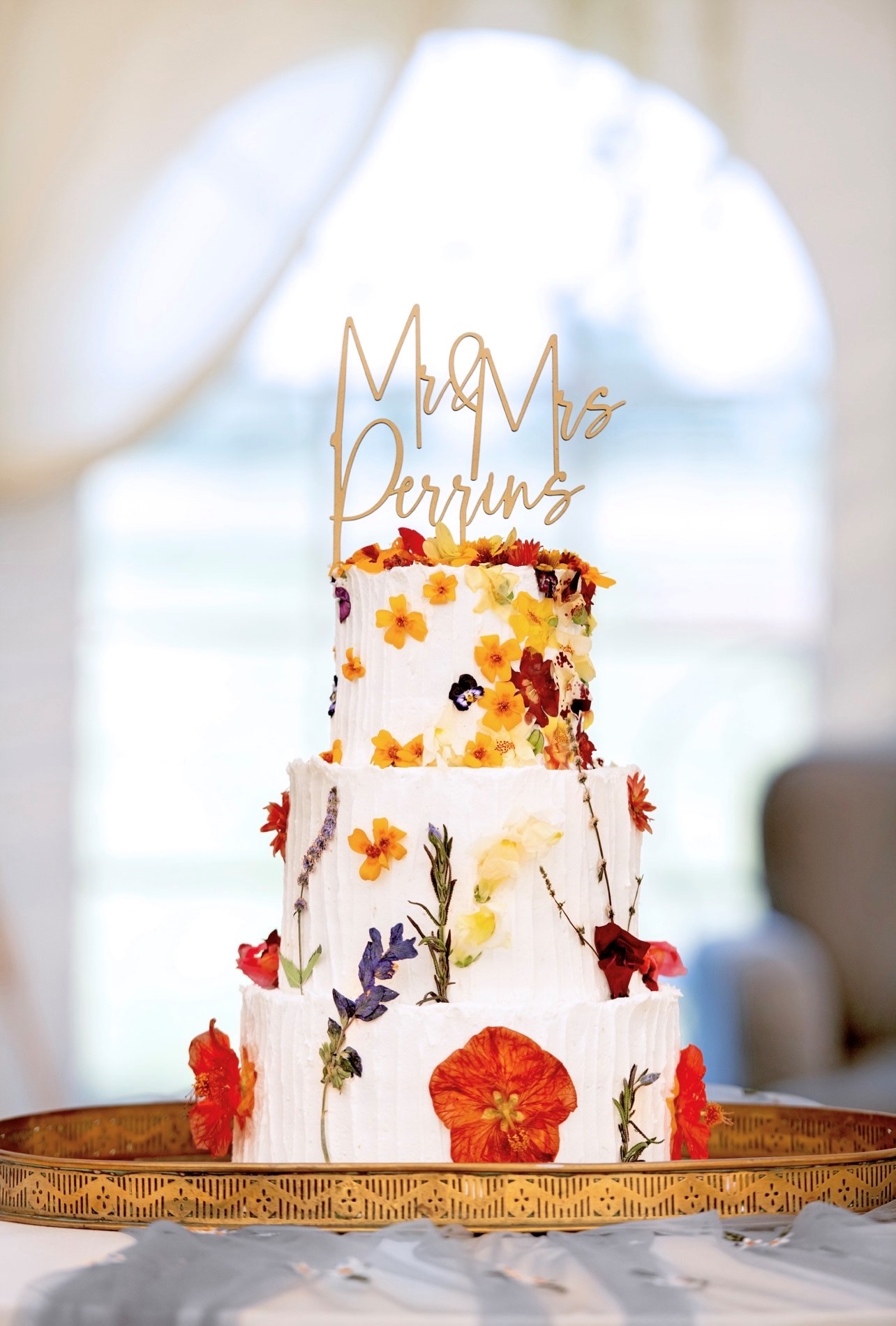 Three tier wedding cake with white icing and yellow and brown flowers