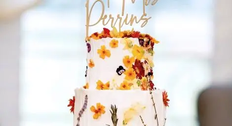 Three tier wedding cake with white icing and yellow and brown flowers