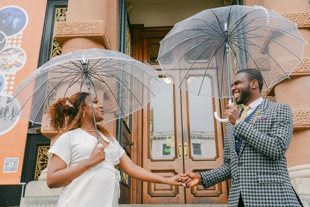 Chic bride and groom with umbrellas in front of Ipswich Town Hall