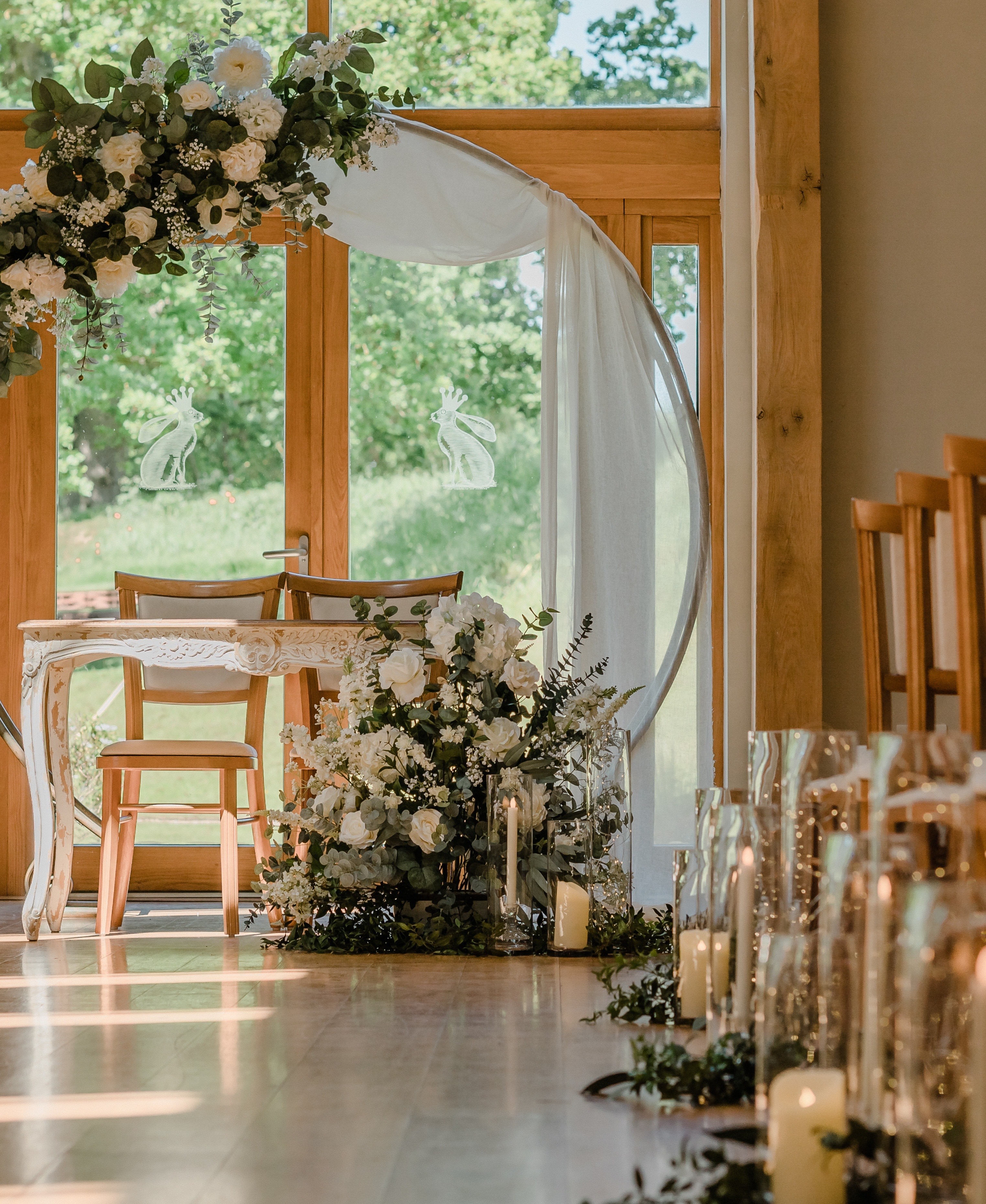 Flower arch with white flowers above table and chairs