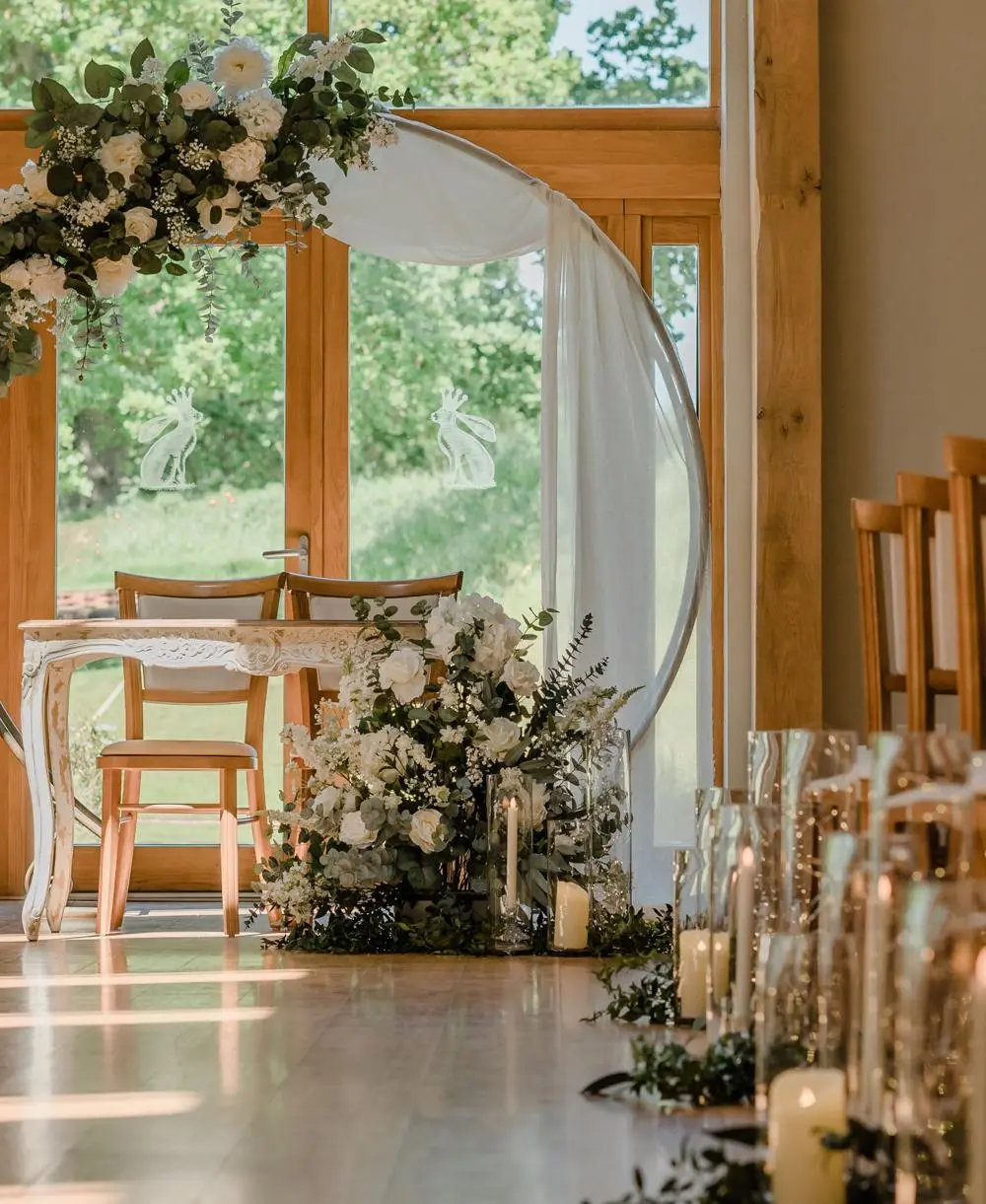 Flower arch with white flowers above table with chairs