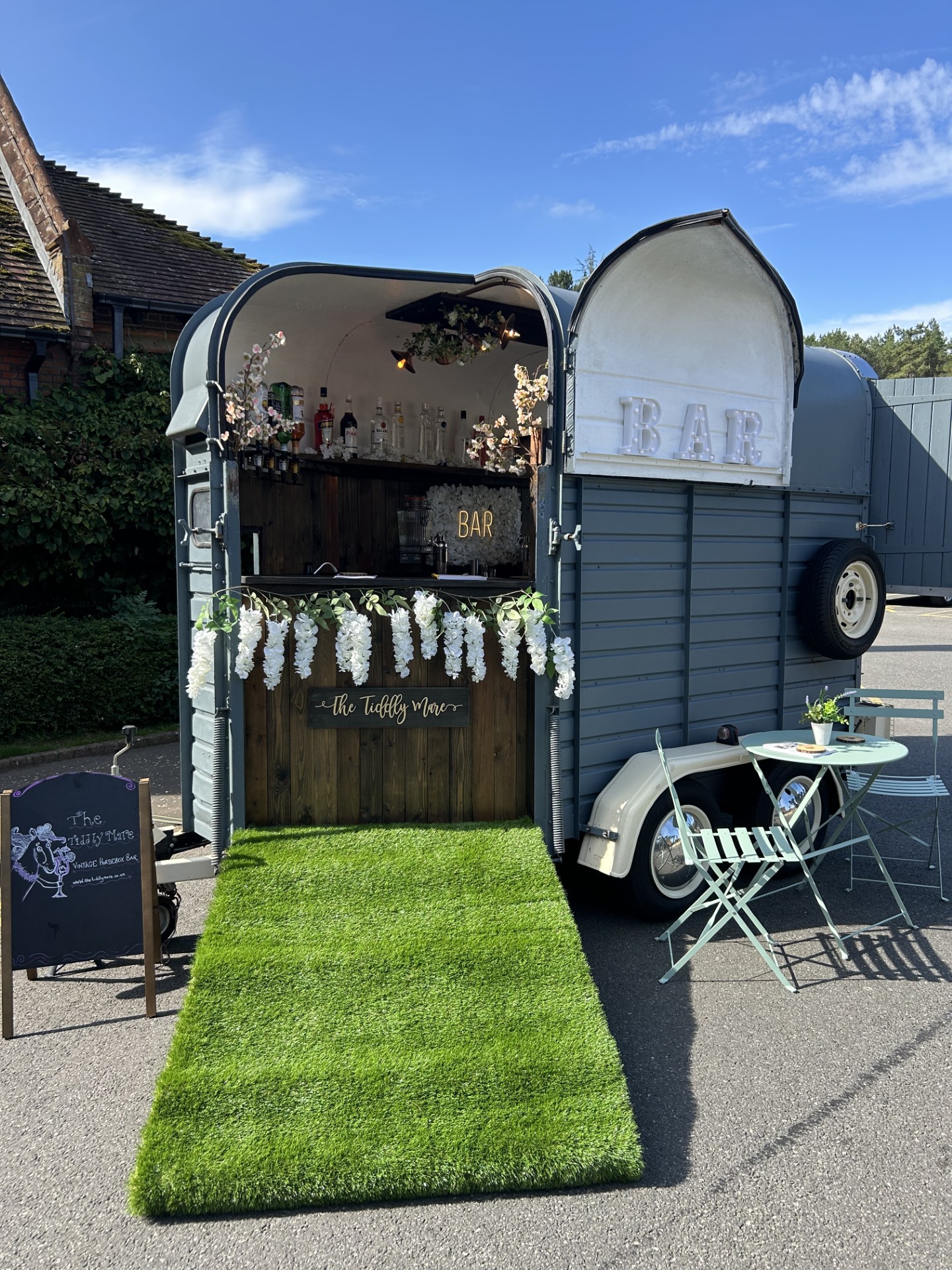 Horsebox bar with green grass like carpet on ramp and flower bunting