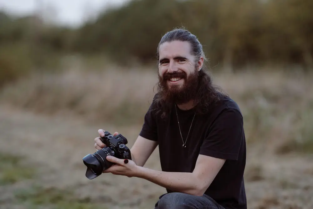 Tom Juggins wedding photographer smiling holding a camera