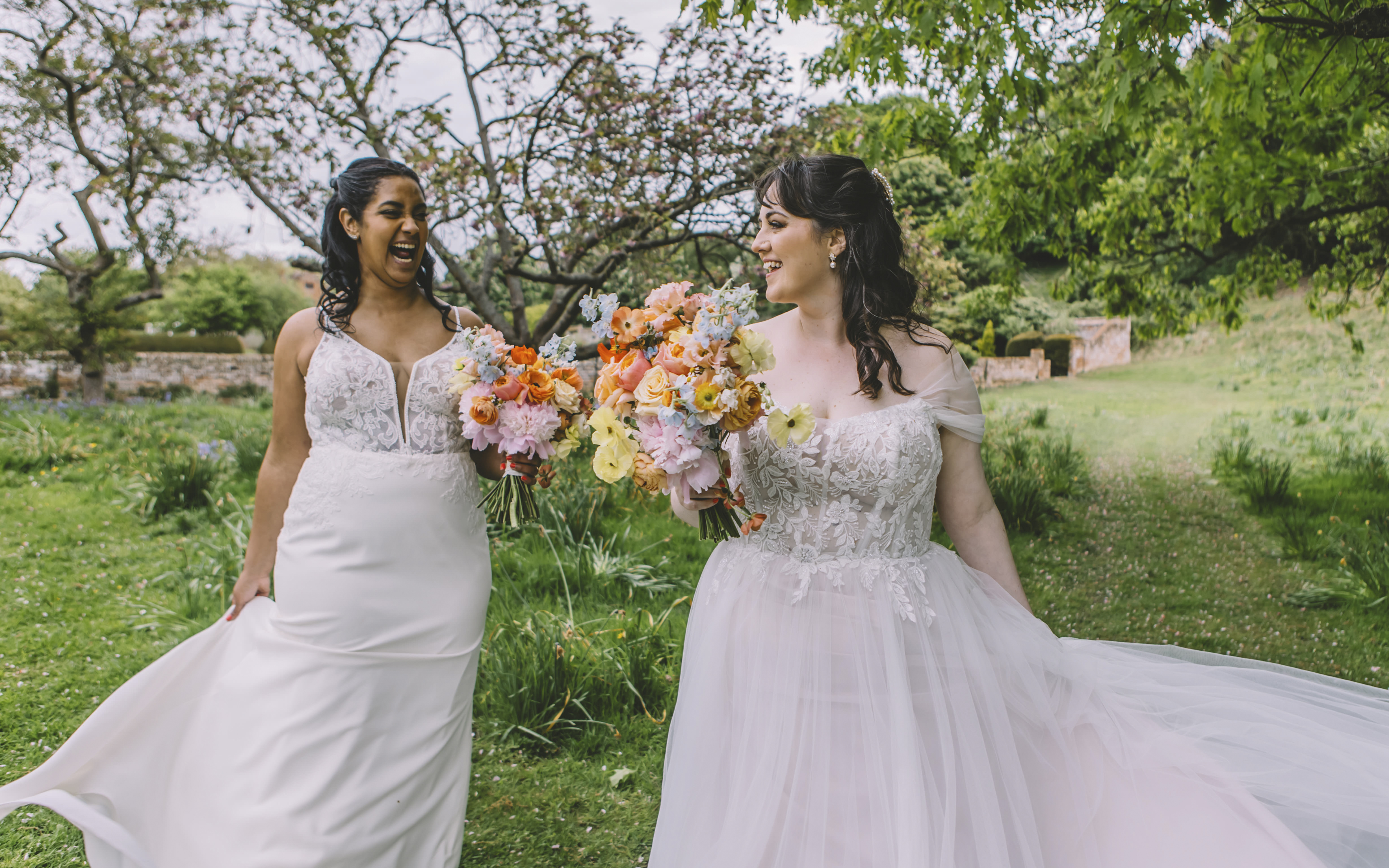 Two brides with beautiful colourful bridal bouquets laughing with each other