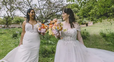 Two brides with beautiful colourful bridal bouquets laughing with each other