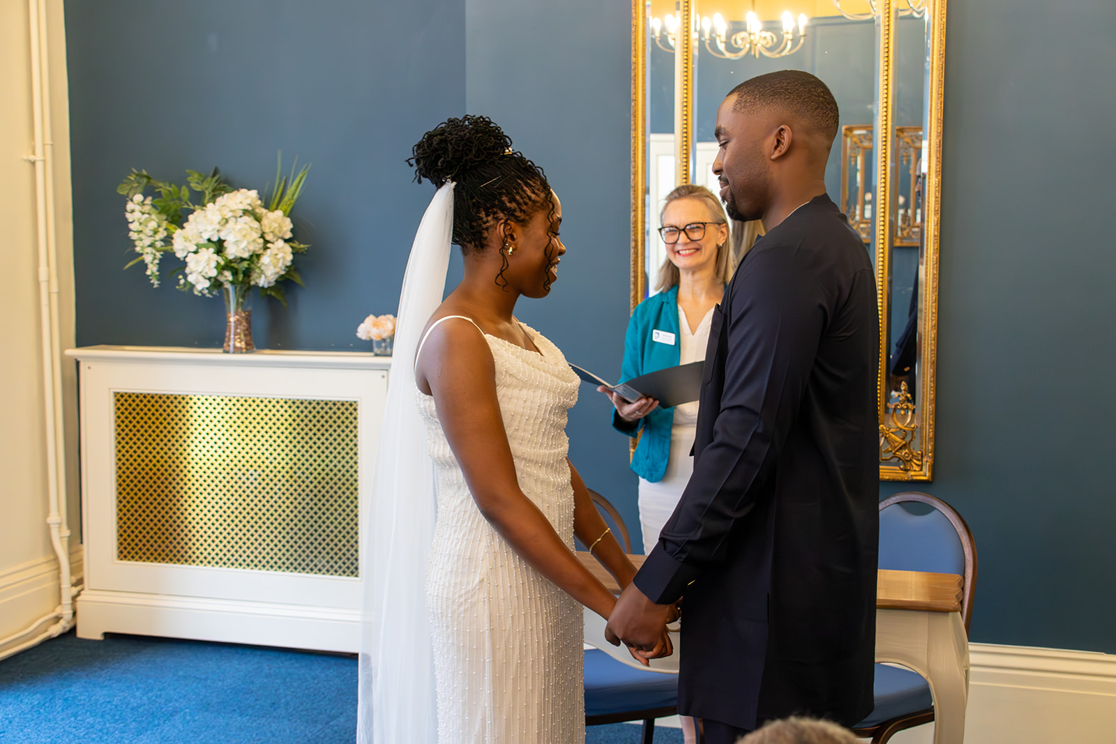Bride and groom holding hands in front of Registrar during their wedding ceremony